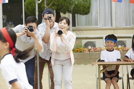 学校运动会上拿着相机拍照的父母们图片