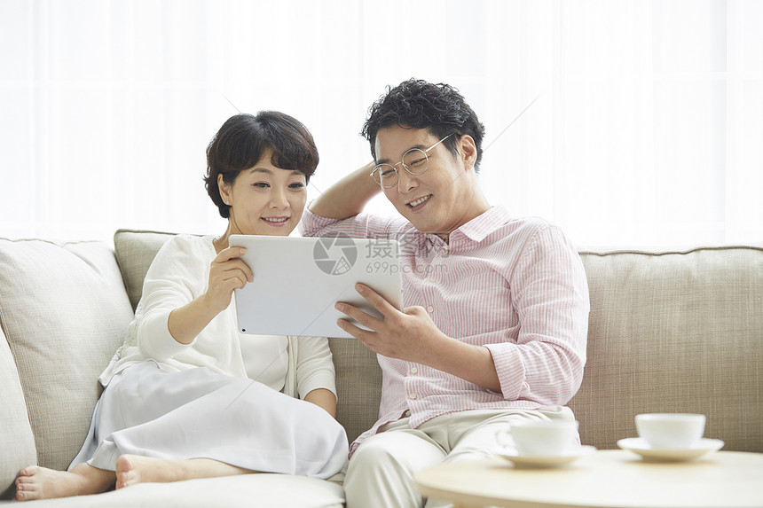 夫妻二人坐在沙发上看平板电脑图片