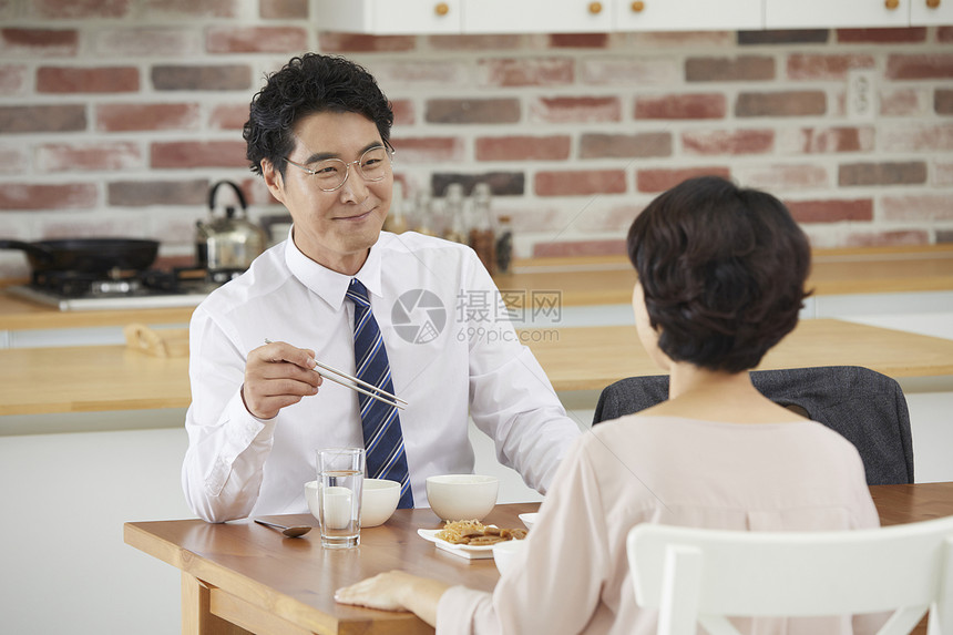 拿着筷子看着妻子微笑的丈夫 图片