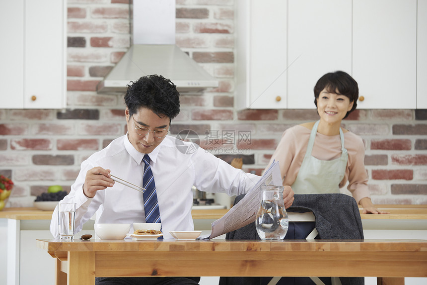 看着报纸用餐的中年男性图片