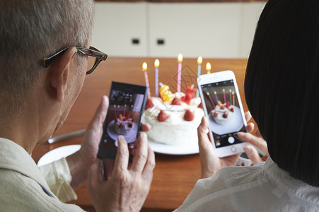 拿手机拍蛋糕的夫妻二人图片
