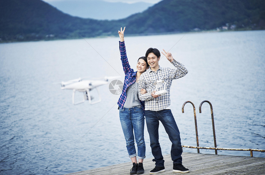 情侣在湖边玩无人机自拍图片