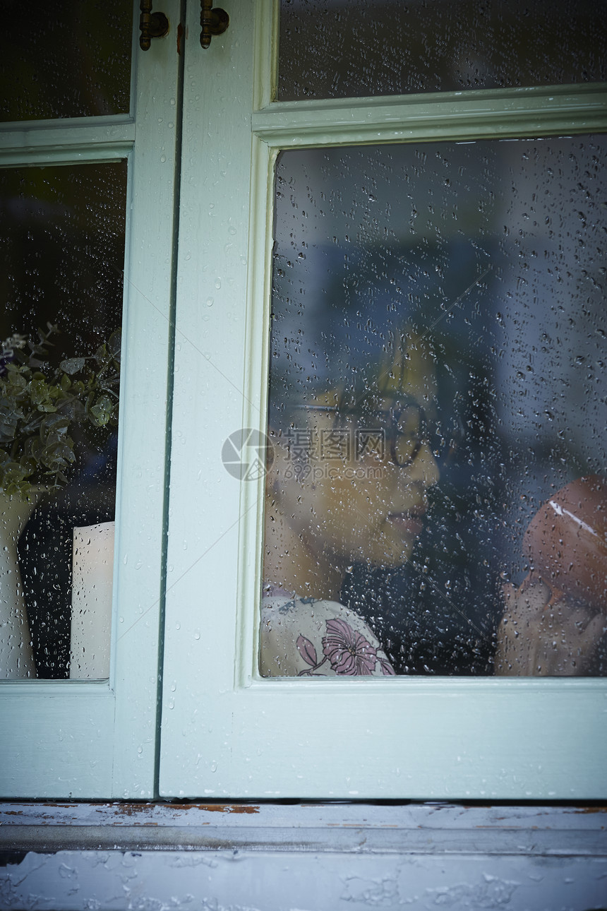 下雨天站在窗户前发呆的孤独女性图片