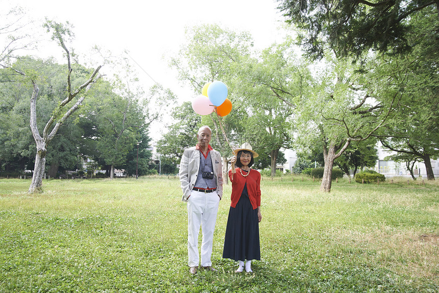 老年夫妇拿气球逛公园画象图片