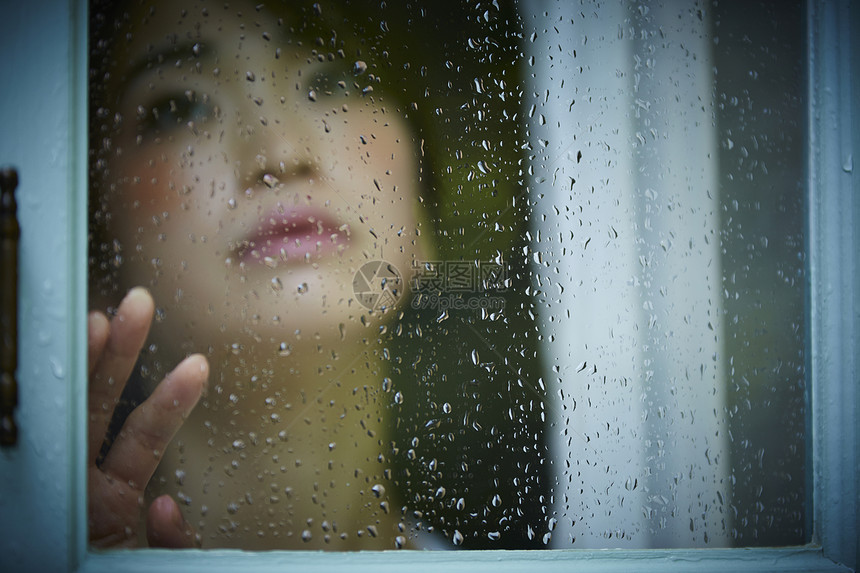 下雨天靠在窗边发呆的孤独女性图片