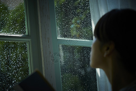 雨夜看向窗外的女青年背景图片