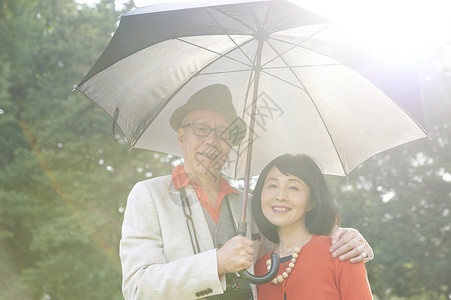 撑着雨伞的开心微笑的夫妇图片