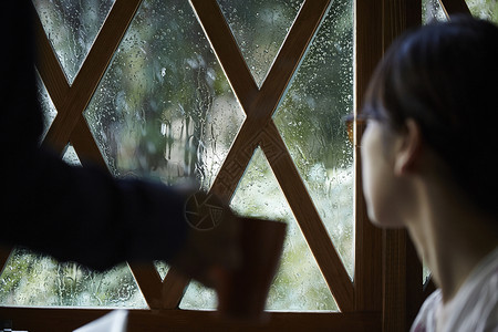 下雨看向窗外的女青年图片