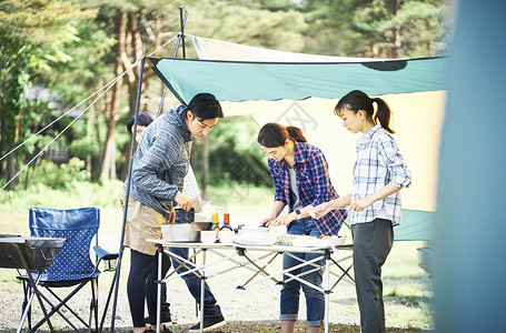 野外露营地制作料理的青年男女图片