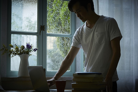 下雨天居家工作的成年男性图片