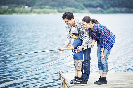 湖泊旁享受钓鱼的一家人图片