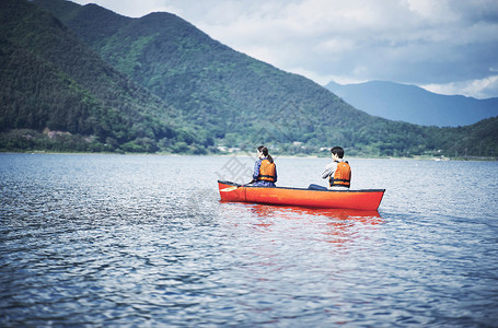 湖泊上穿着救生衣划船的夫妇背影背景图片