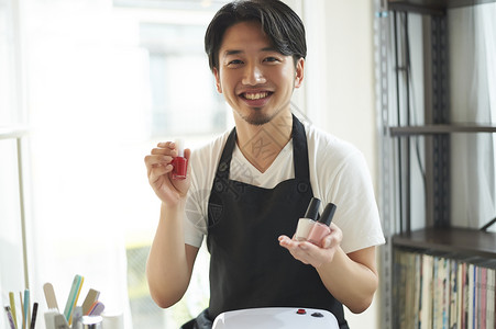 美甲沙龙拿着指甲油开心微笑的男性美甲师图片