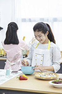 厨房里穿着围裙制作料理的小女孩图片