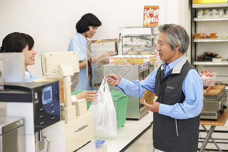 便利店收银台结账的老年顾客图片