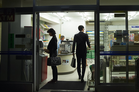 便利店门口夜晚便利店购物的顾客背景