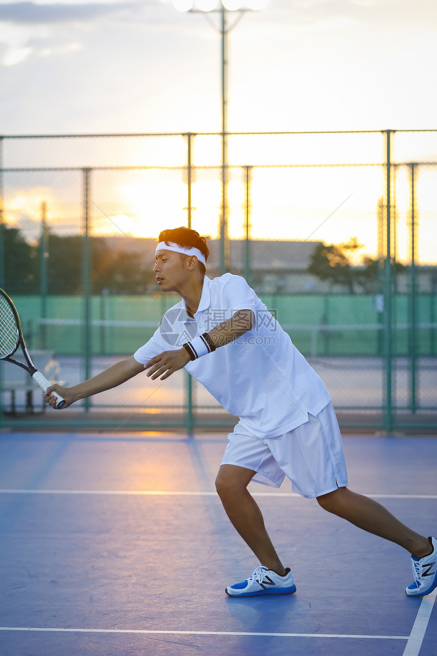 夕阳下打网球的青年男性图片