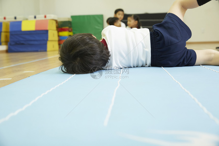 小男孩在垫子上锻炼的背影图片