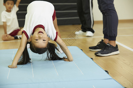 穿着体操服在垫子上锻炼的小女孩高清图片