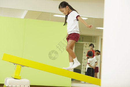 年轻的小女孩体操课堂练习平衡木图片