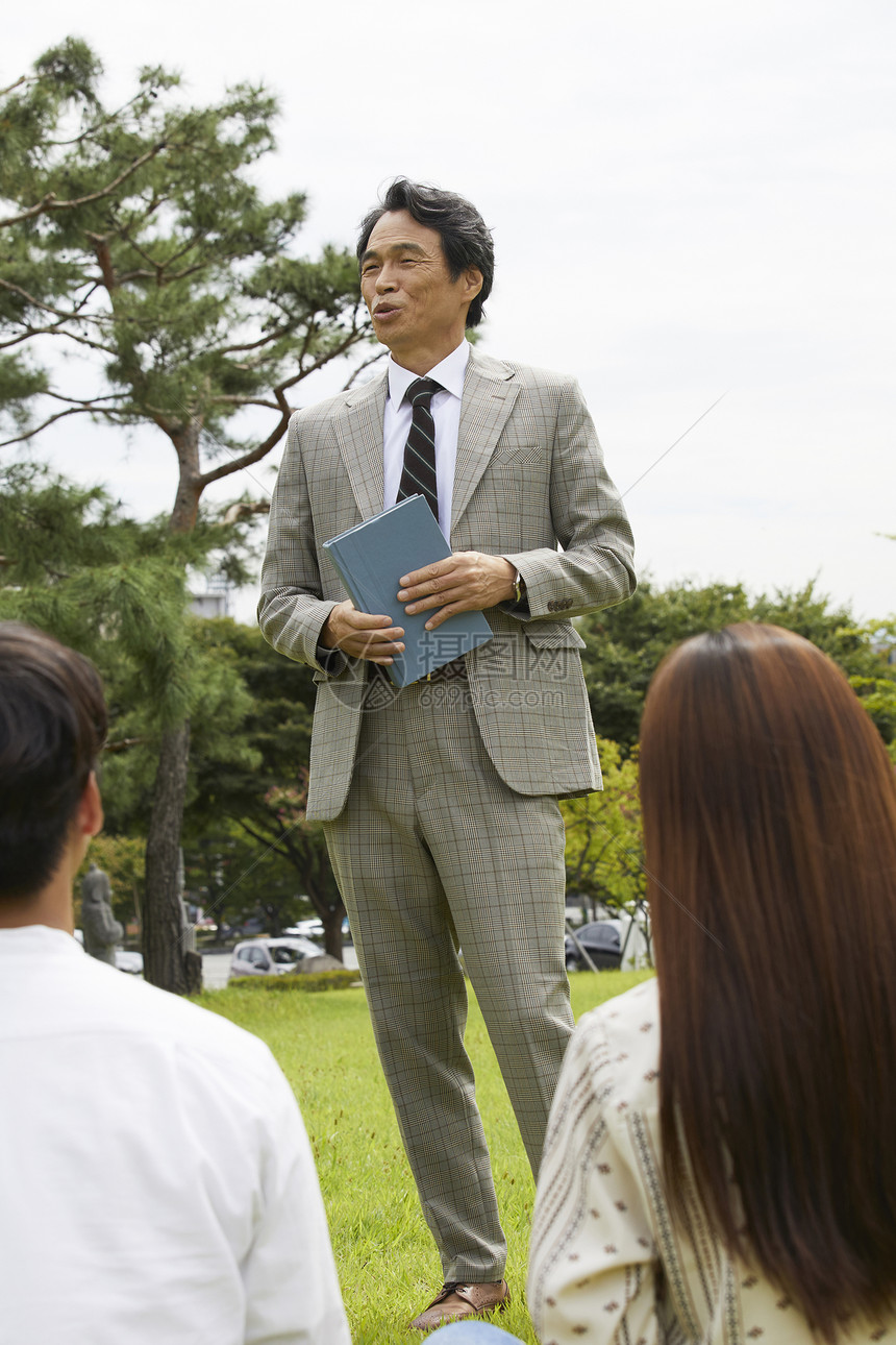 大学教授和学生们围坐在草地上分享交流图片