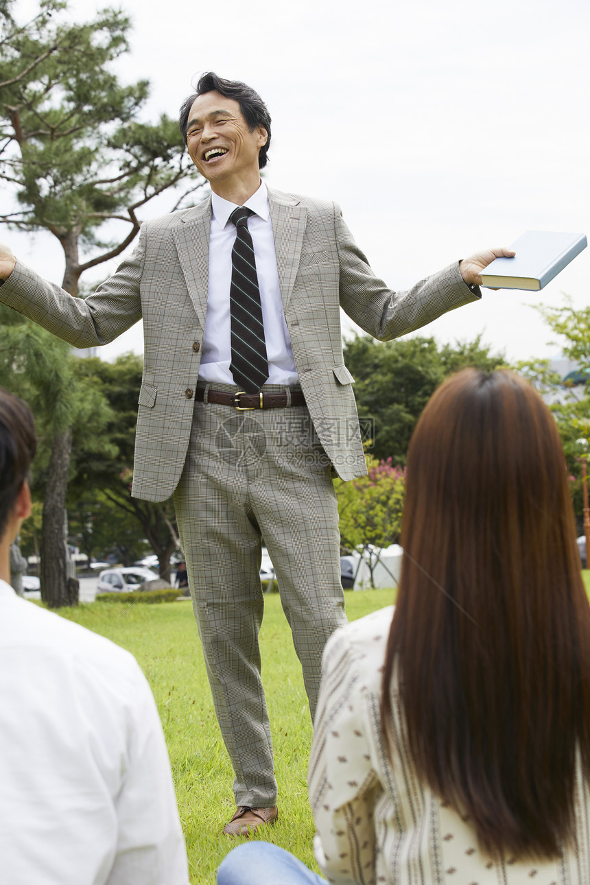 大学教授和学生们围坐在草地上分享交流图片