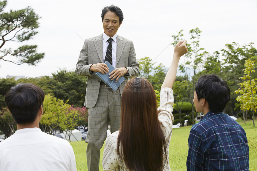 大学教授和学生们围坐在草地上分享交流图片