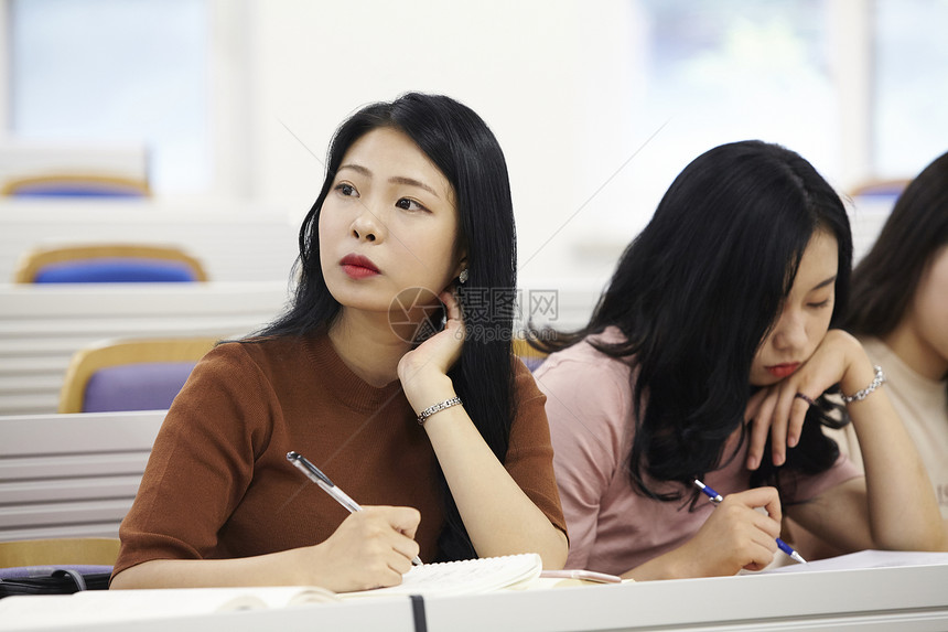 课堂上拿着笔的女大学生图片