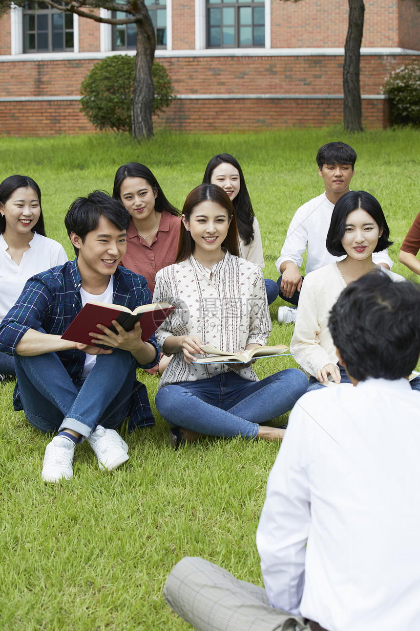 户外草坪上拿着书本的大学生图片