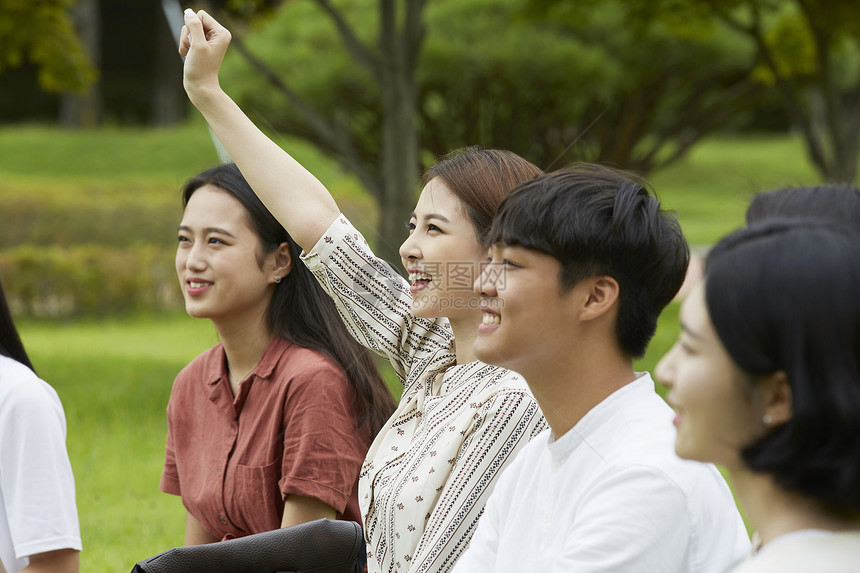 户外举手提问微笑的女大学生图片