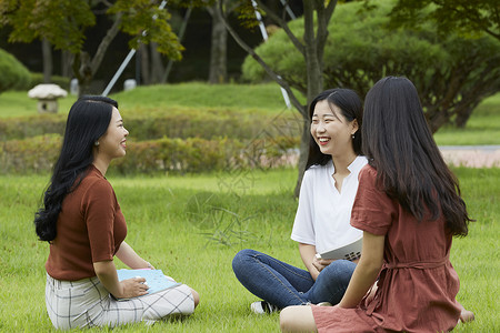 户外草坪上聊天的女大学生图片