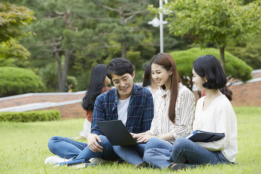 户外看着笔记本电脑的大学生图片