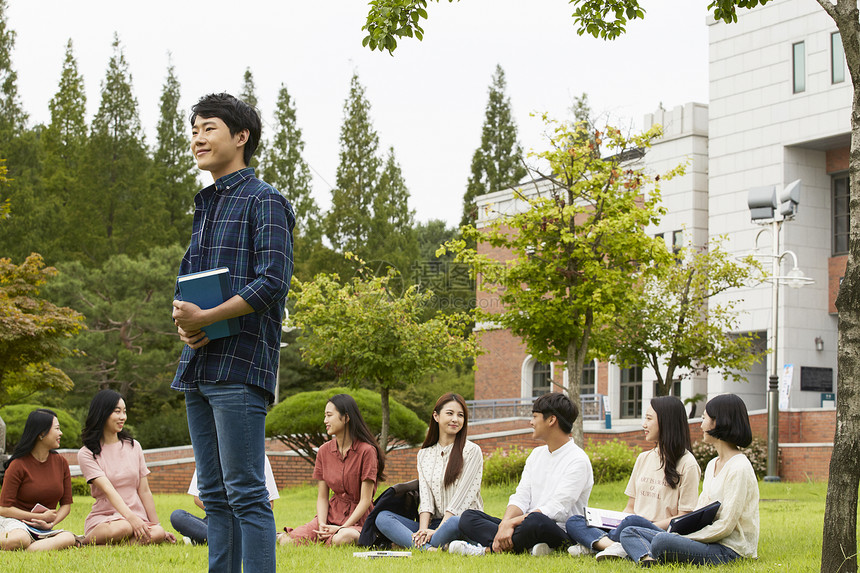 校园草坪上拿着书本的大学生图片