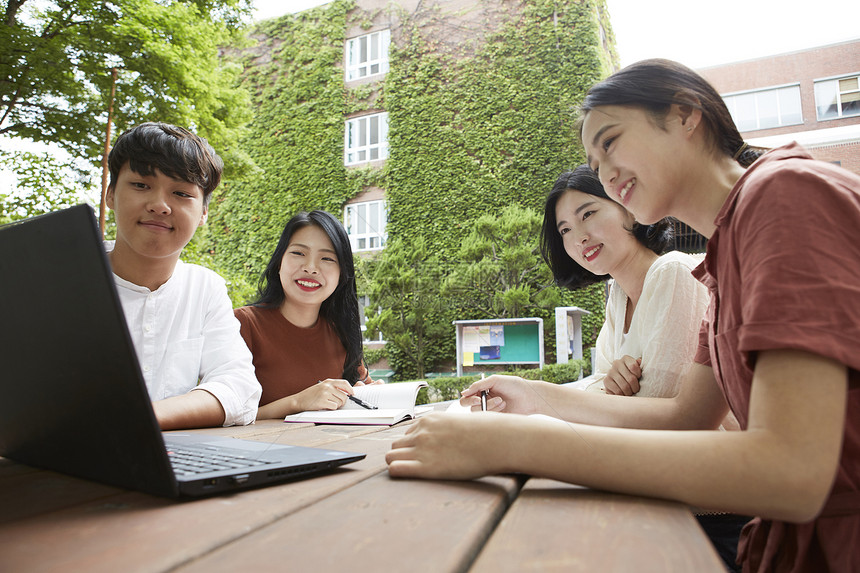 户外看着笔记本电脑学习的大学生图片