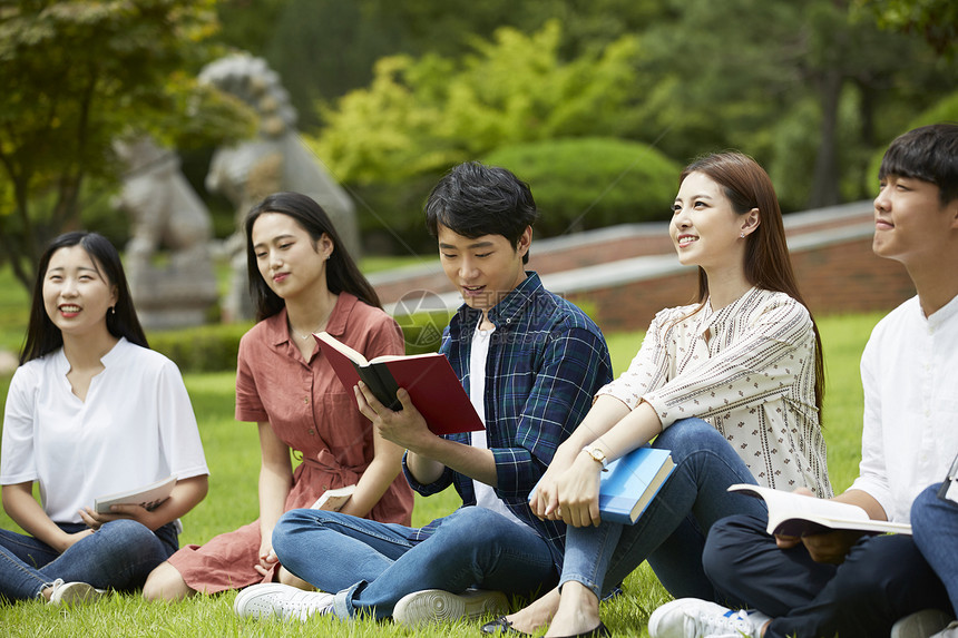 户外草坪拿着书籍的大学生图片