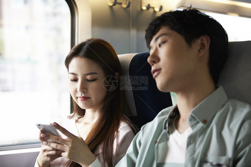 火车上玩着手机的年轻女性图片