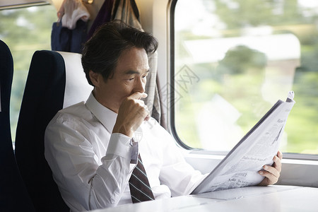 火车上看报纸的成年男子图片