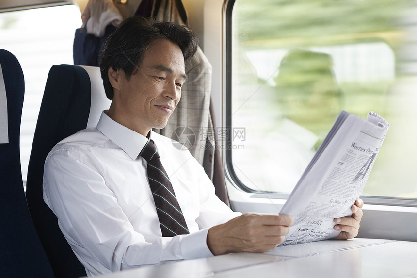 火车上看着报纸的成年男子图片