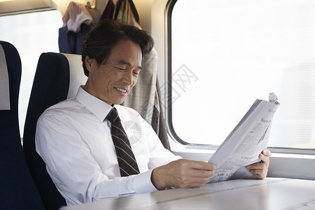 火车上看报纸微笑的成年男子图片