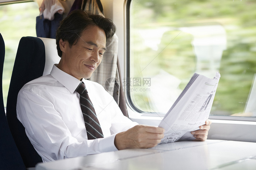火车上看报纸微笑的成年男性图片