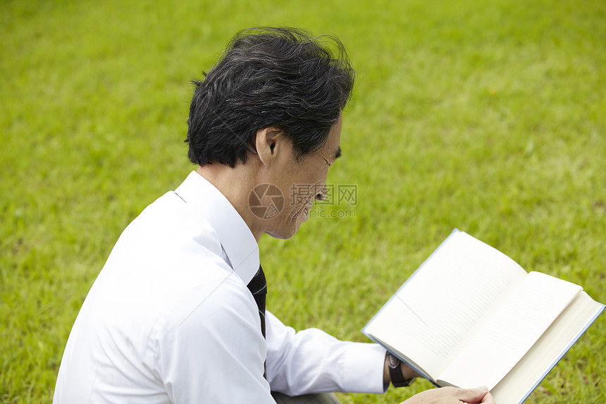坐在草坪上阅读的大学教练图片
