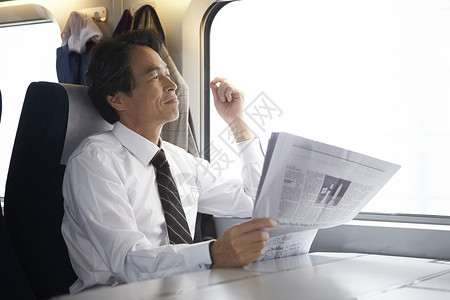 火车上看报纸的商务男性图片