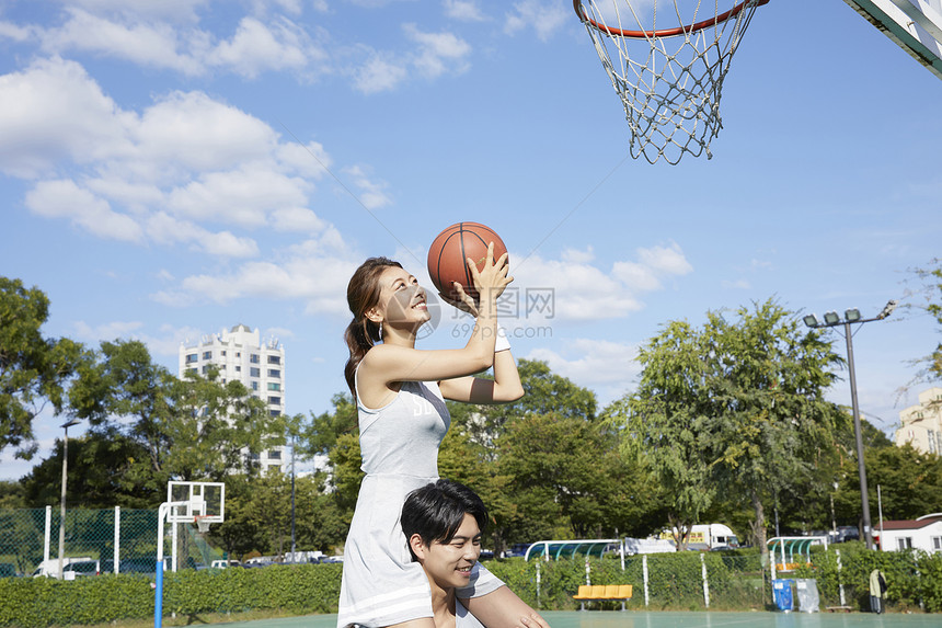 女孩坐在男孩肩膀上投篮图片