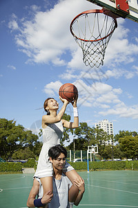 女孩坐在男孩肩上投篮图片