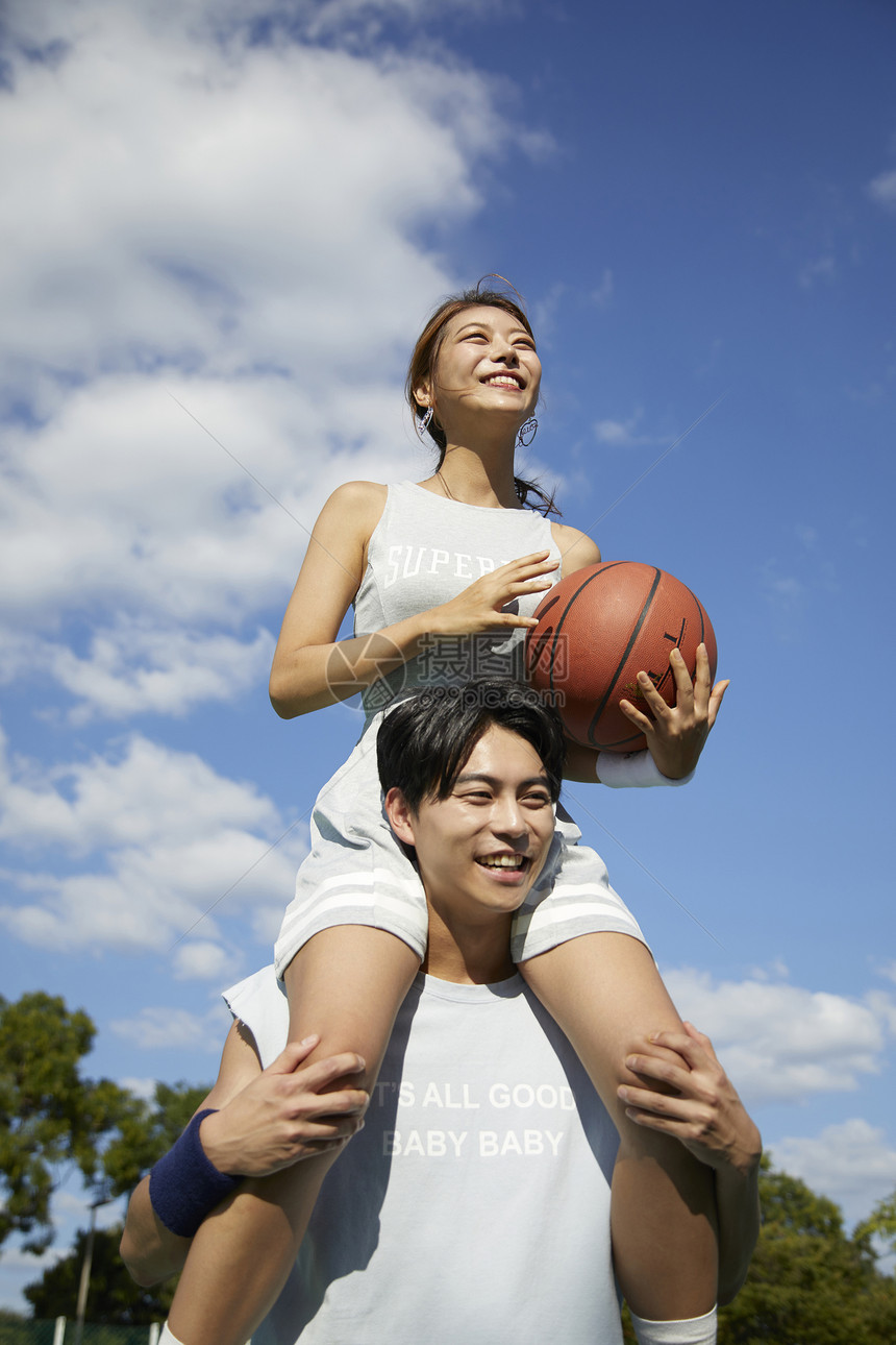 女孩坐在男孩肩上投篮图片