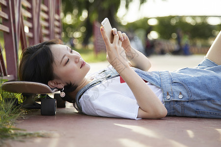 滑板女孩躺着看手机图片