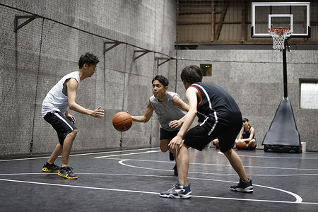 年轻男性在室内篮球场打球高清图片