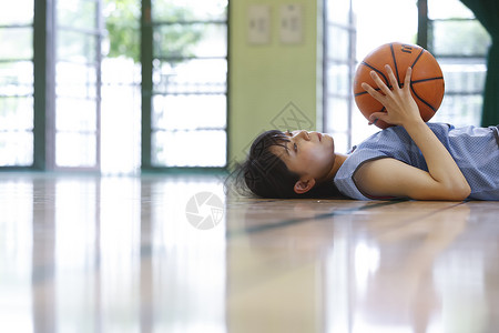 拿着篮球躺在地上休息的女性图片