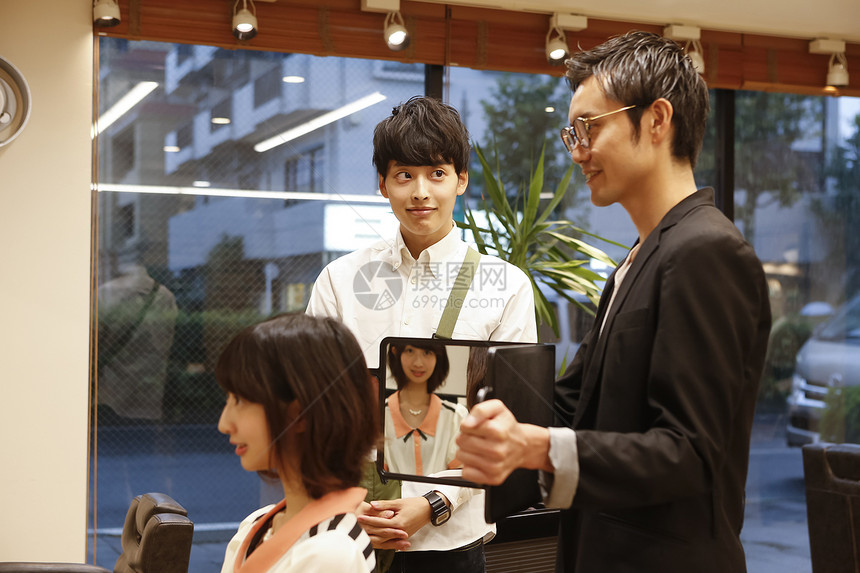 美发沙龙为顾客展示造型的美发师图片