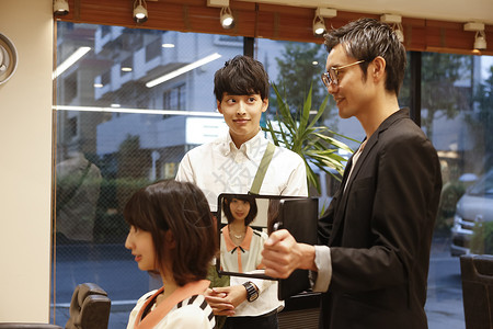 美发沙龙为顾客展示造型的美发师背景图片